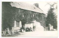 [Cavaliers à cheval dans une rivière, femme à pied, maison en arrière plan.]