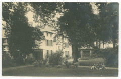 Manoir de la Salle à Saint-Erblon au second plan. 
Deux enfants et deux chiens assis dans le jardin au premier plan.