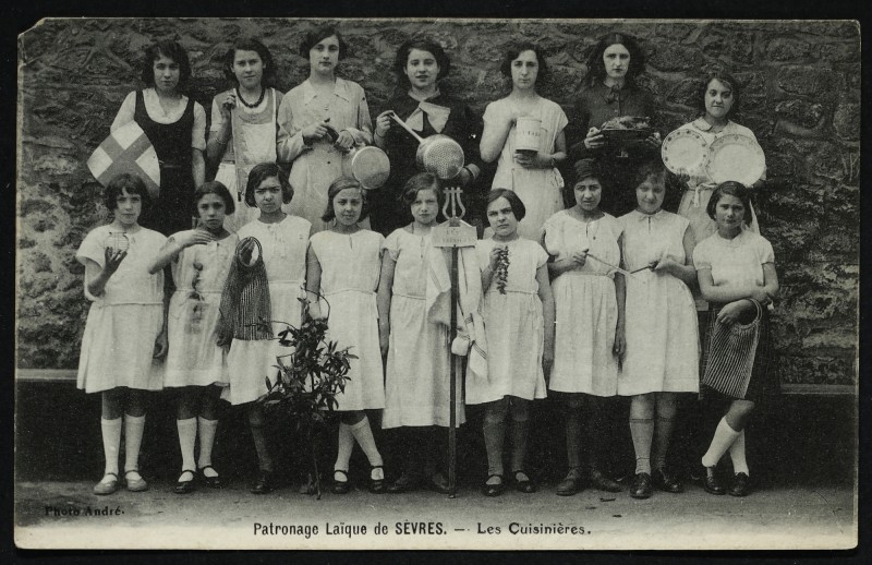 Carte postale ancienne Patronage Laïque de Sèvres - Les cuisinières. Groupe de jeunes filles apprenant la cuisine et posant en groupe, certaines munies d'ustensiles de cuisine. à Sèvres