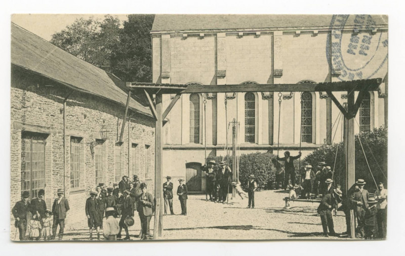 Carte postale ancienne [Familles assemblées dans une cour d'école avec des portiques et des jeux à côté d'une chapelle.]