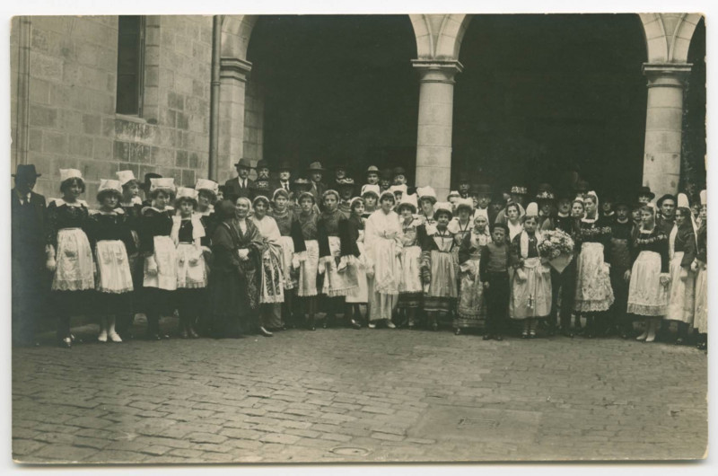 Carte postale ancienne [RENNES, Fête. - Ensemble de groupes folkoriques dans une cour devant des piliers.]