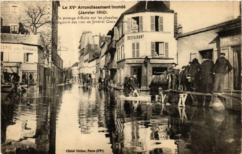 Carte postale ancienne Le XVe Arrondissement inondé (Janvier 1910) - Un Passage difficile sur les planches à l'encoignure des rues Javel Croix-Nivert à Paris 15e