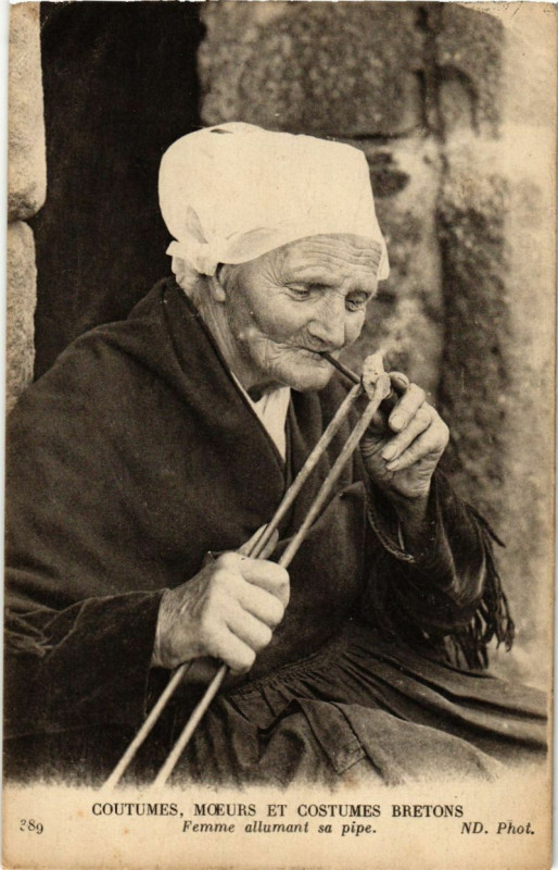 Carte postale ancienne Coutumes Moeurs et Costumes Bretons - Femme allumant sa Pipe