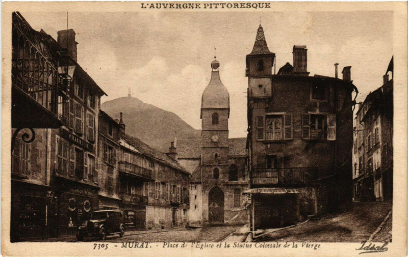 Carte postale ancienne Murat - Place de l'Eglise et la Statue Colossale de la Vierge à Murat