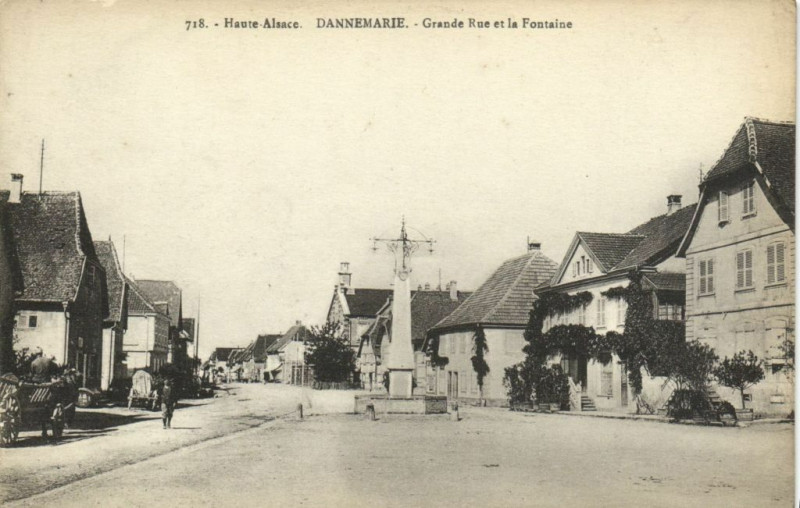 Carte postale ancienne Haute - Alsace Dannemarie Grande Rue et la Fontaine à Dannemarie